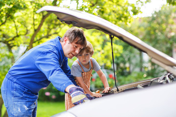 young father teaching his little son to change motor oil in fami