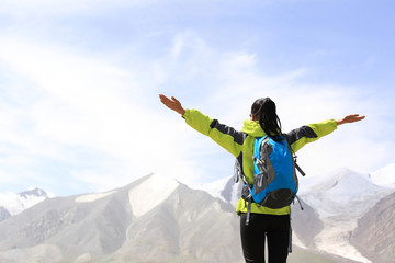 Wall Mural - cheering young woman hiker open arms mountain peak 