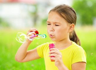 Wall Mural - Little girl is blowing a soap bubbles