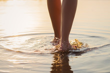 Woman Walking In The Shallow Water At Sunset