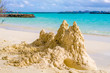Sand castle on the beach in front of ocean with Male in the back