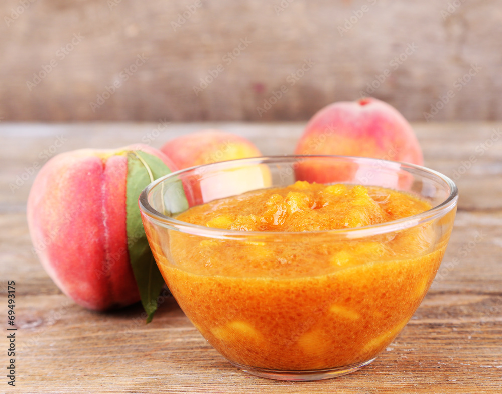 tasty peach jam with fresh peaches on wooden table