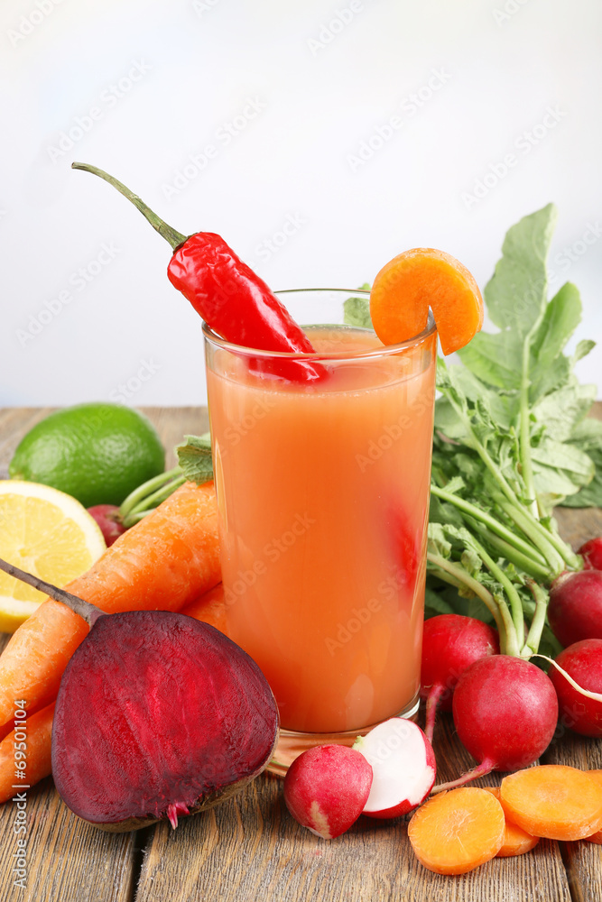 Fresh carrot juice with vegetables on wooden table
