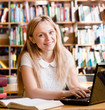 © Ermolaev Alexandr - happy female student with laptop in library