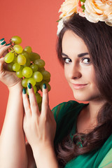 beautiful young woman wearing wreath and holding green grapes ag