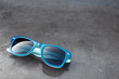 blue plastic sunglasses and dark glossy background