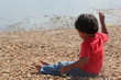 young indian toddler boy kid playing sand shore watching sea