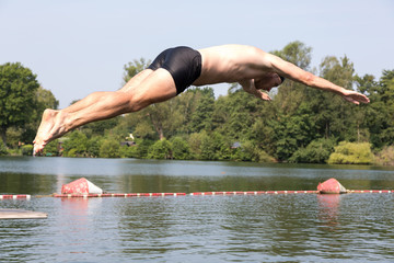 Wall Mural - Man jumping off diving board at swimming pool