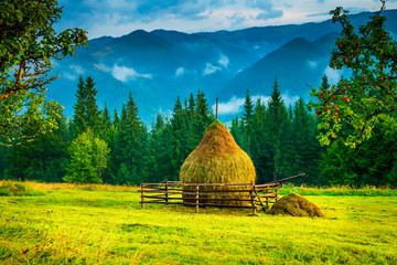 Wall Mural - amazing mountain landscape with fog and a haystack