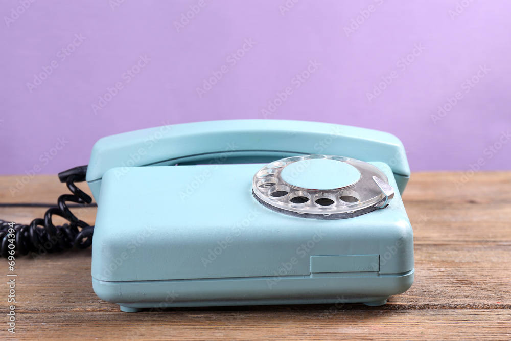 Retro turquoise telephone on wooden table, on color background