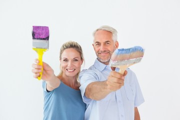Aufkleber - Happy couple holding paintbrushes smiling at camera