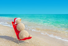 Sandy Snowman In Santa Hat Sunbathing In Beach Lounge.