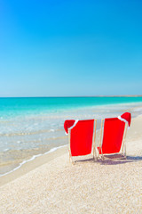 Poster - Santa hat on chaise longues at white sand beach against the sea