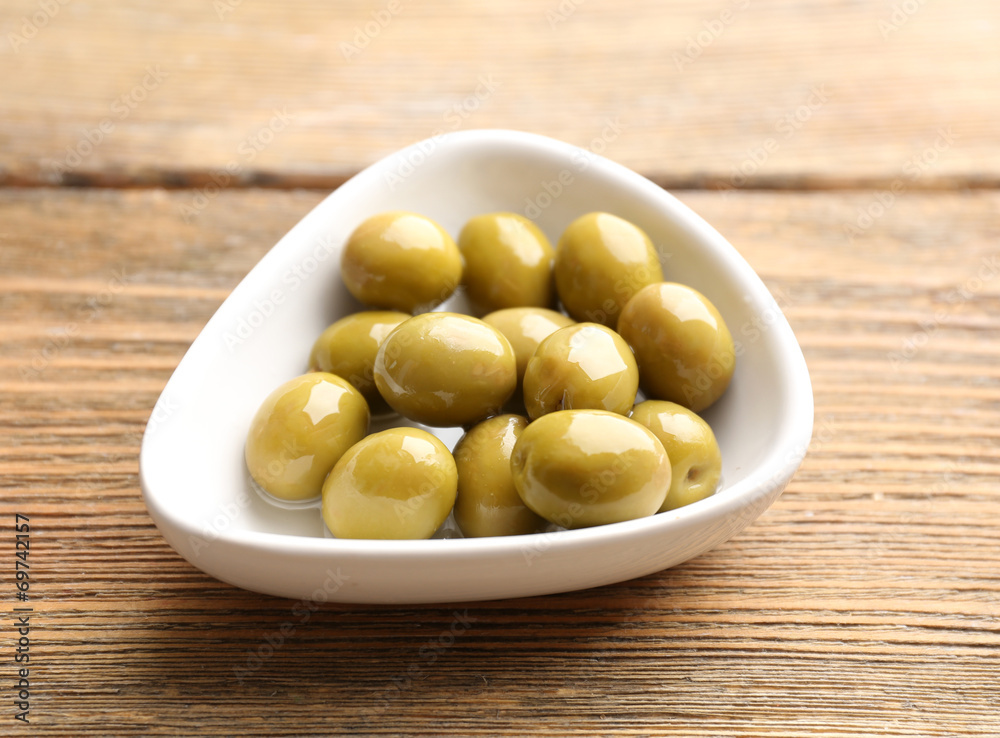 Green olives in bowl on table close-up