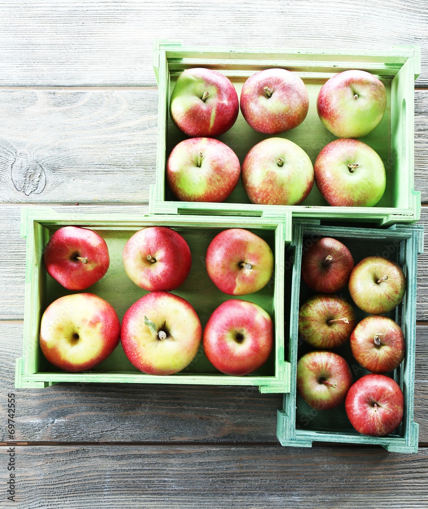 Juicy apples in boxes on wooden background