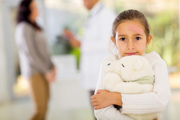 Wall Mural - Girl with adhesive bandage on her face holding a teddy bear