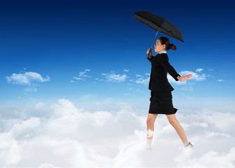 Poster - Composite image of young businesswoman holding umbrella