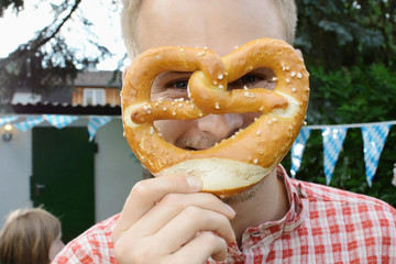 Wall Mural - Mann hält Brezel vor Gesicht