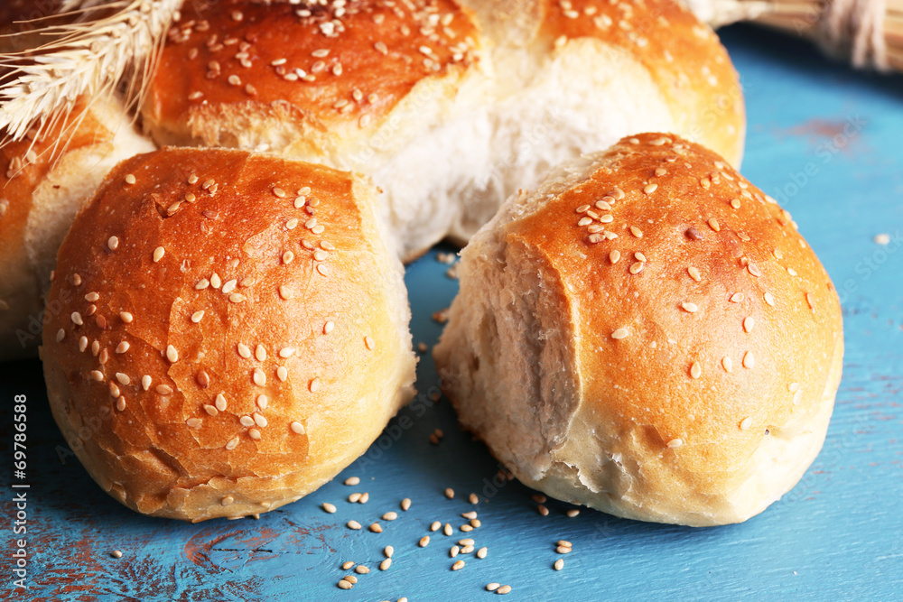 Tasty buns with sesame on color wooden background