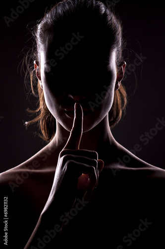Cuadros en Lienzo unknown woman with the face in the shadow holding finger on lips
