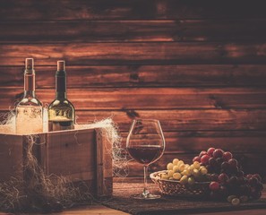 Bottles of red and white wine, glass in a wooden interior