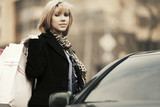 Fototapeta Młodzieżowe - Young fashion woman with shopping bags on the car parking