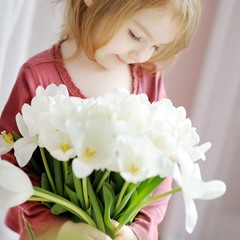 Wall Mural - Adorable little girl with tulips by the window