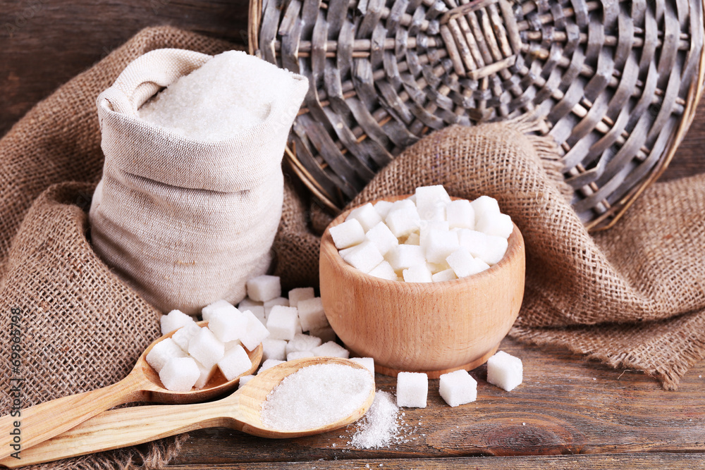 Refined sugar in bag and bowl on wooden background