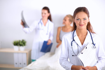 Smiling female doctor with a folder in uniform standing at