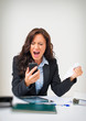 © M-Production - Angry businesswoman with phone in office.