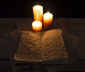 Open black magic book with candles