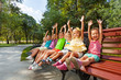 © Sergey Novikov - Group of kids on the bench cheering lifting hands