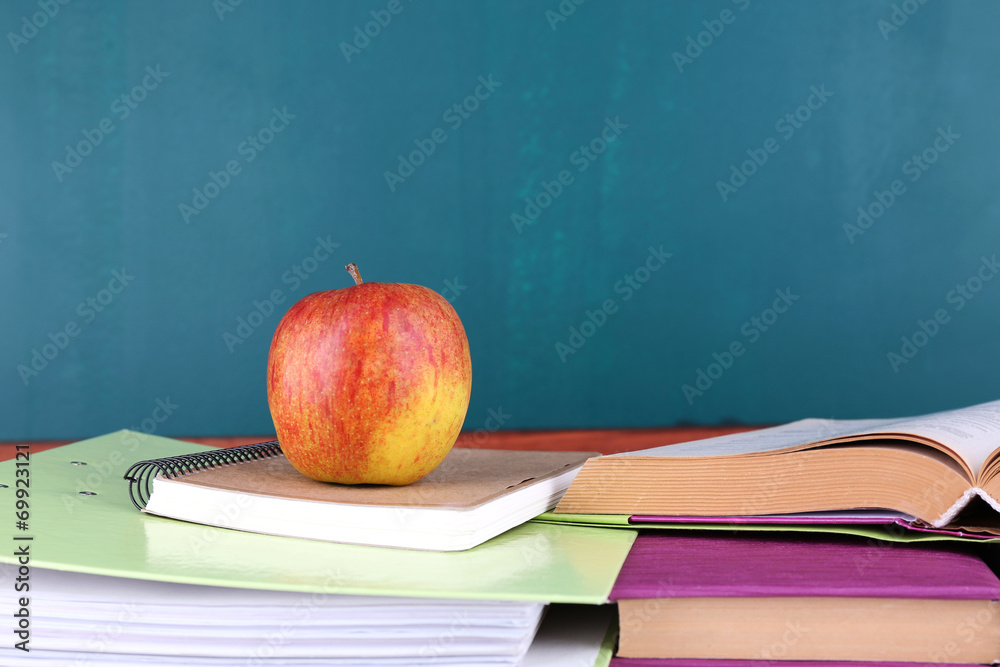 School supplies on table on blackboard background