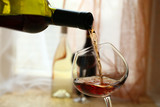 Fototapeta Storczyk - Red wine pouring into wine glass, close-up