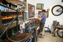 Man In Bike Shop Fixing Bike Frame