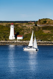 Fototapeta Łazienka - White Sailboat Passing a White Lighthouse in Blue Water