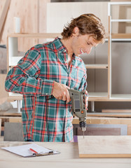 Carpenter Drilling Wood At Workshop