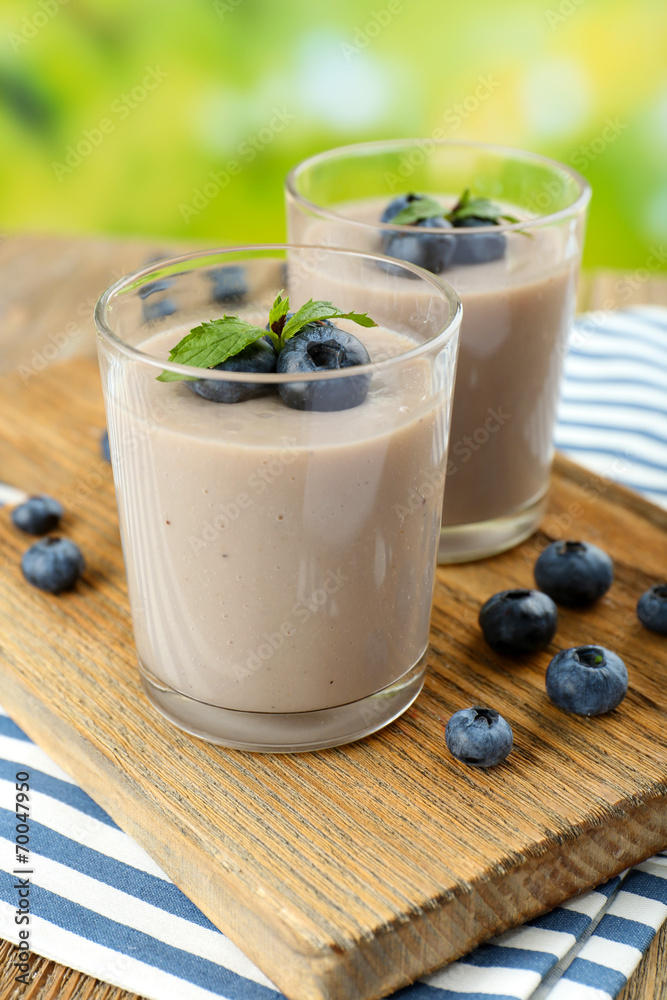 Delicious berry mousse in glasses on table on bright background