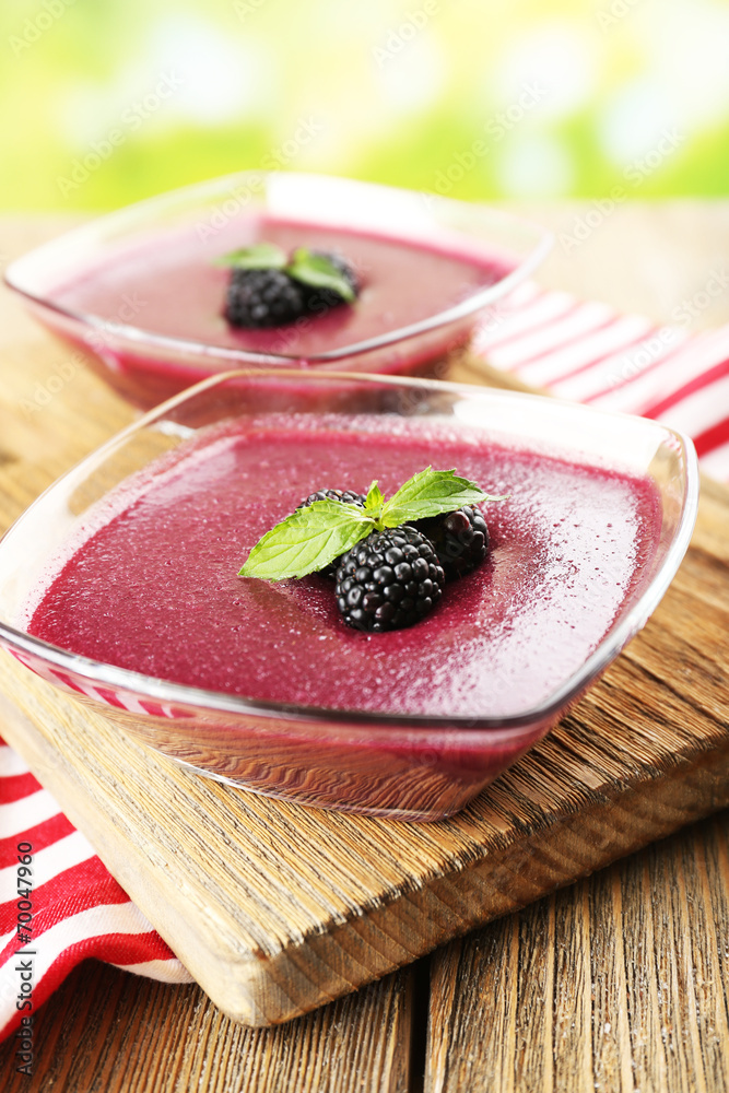 Delicious berry mousse in bowls on table on bright background