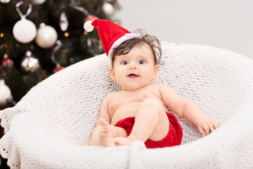 Canvas Print - Cute baby girl sitting in front of a Christmas tree