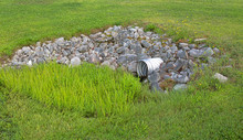 Storm Culvert Surrounded By Rocks And Grass