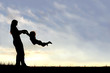 Silhouette of mother Playing with Child Outside at Sunset