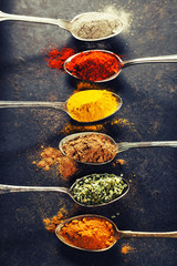 Wall Mural - Colorful spices in metal spoons