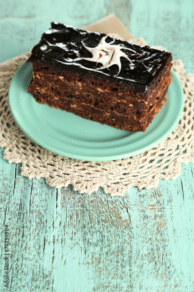 Chocolate cake on plate on color wooden background