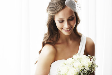 Wall Mural - Young bride in wedding dress holding bouquet, studio shot .