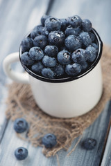 Wall Mural - Enameled cup with ripe blueberries, close-up