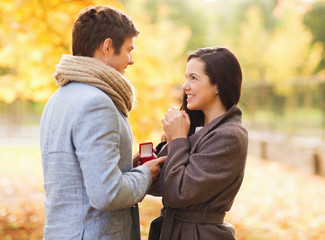 Sticker - smiling couple with red gift box in autumn park