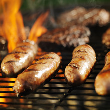Cooking Bratwursts Over Flaming Grill