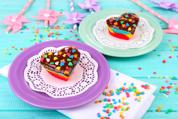 Wall Mural - Delicious rainbow cakes on plates, on color wooden background