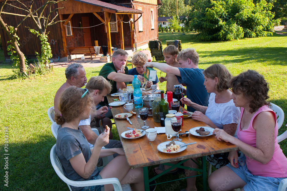 Duża rodzina podczas posiłku w letnie popołudnie - obrazy, fototapety, plakaty 